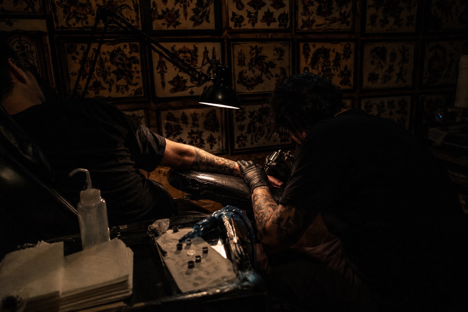 Tattoo artist mid-session in a dark studio